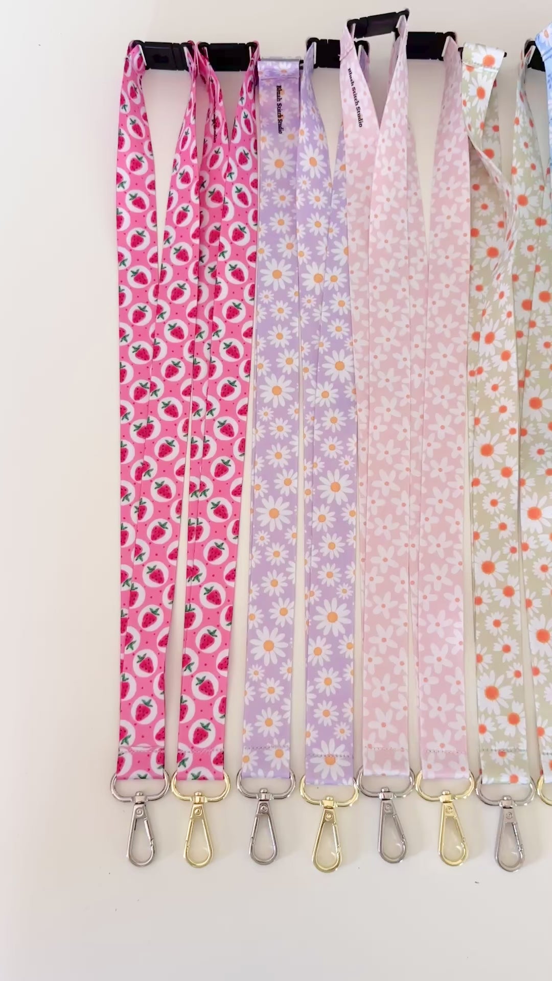 Set of colorful patterned lanyards hanging on a rack against a white background