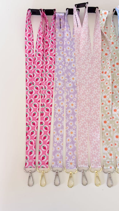 Set of colorful patterned lanyards hanging on a rack against a white background