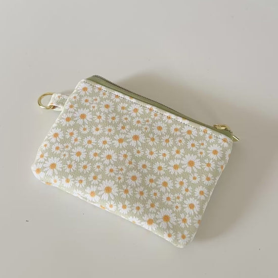 green daisy Floral-patterned coin purse  with coins and cards on a light background