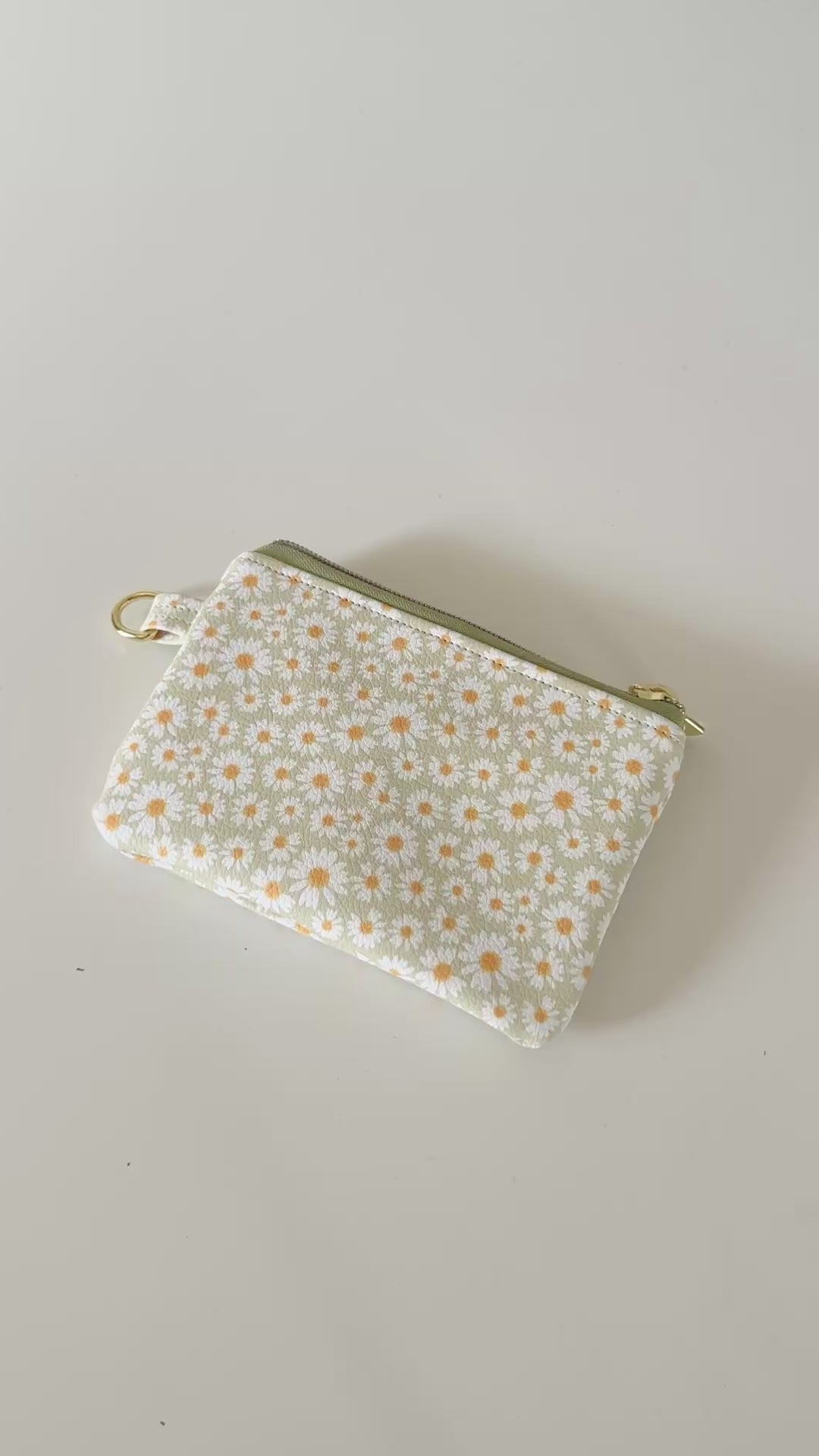 green daisy Floral-patterned coin purse  with coins and cards on a light background