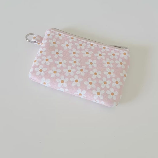 Floral-patterned coin purse with coins and cards on a light background