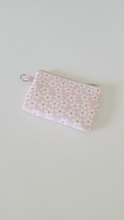 Floral-patterned coin purse with coins and cards on a light background