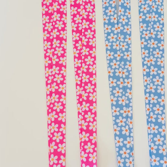 Four  daisy floral lanyards in pink, blue, and yellow on a white background
