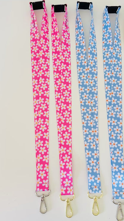 Four  daisy floral lanyards in pink, blue, and yellow on a white background