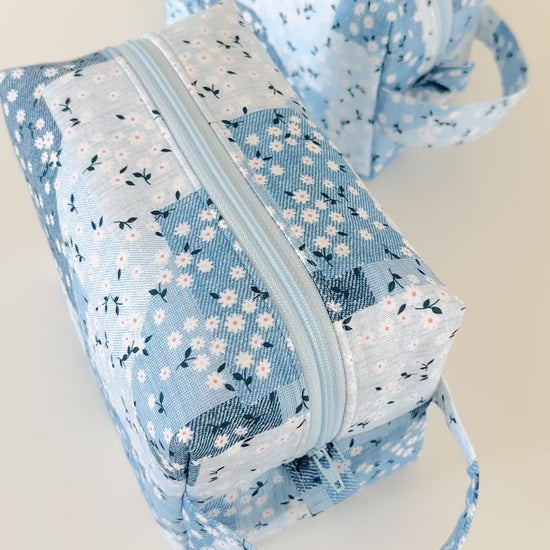 Three blue floral fabric pouches on a light background