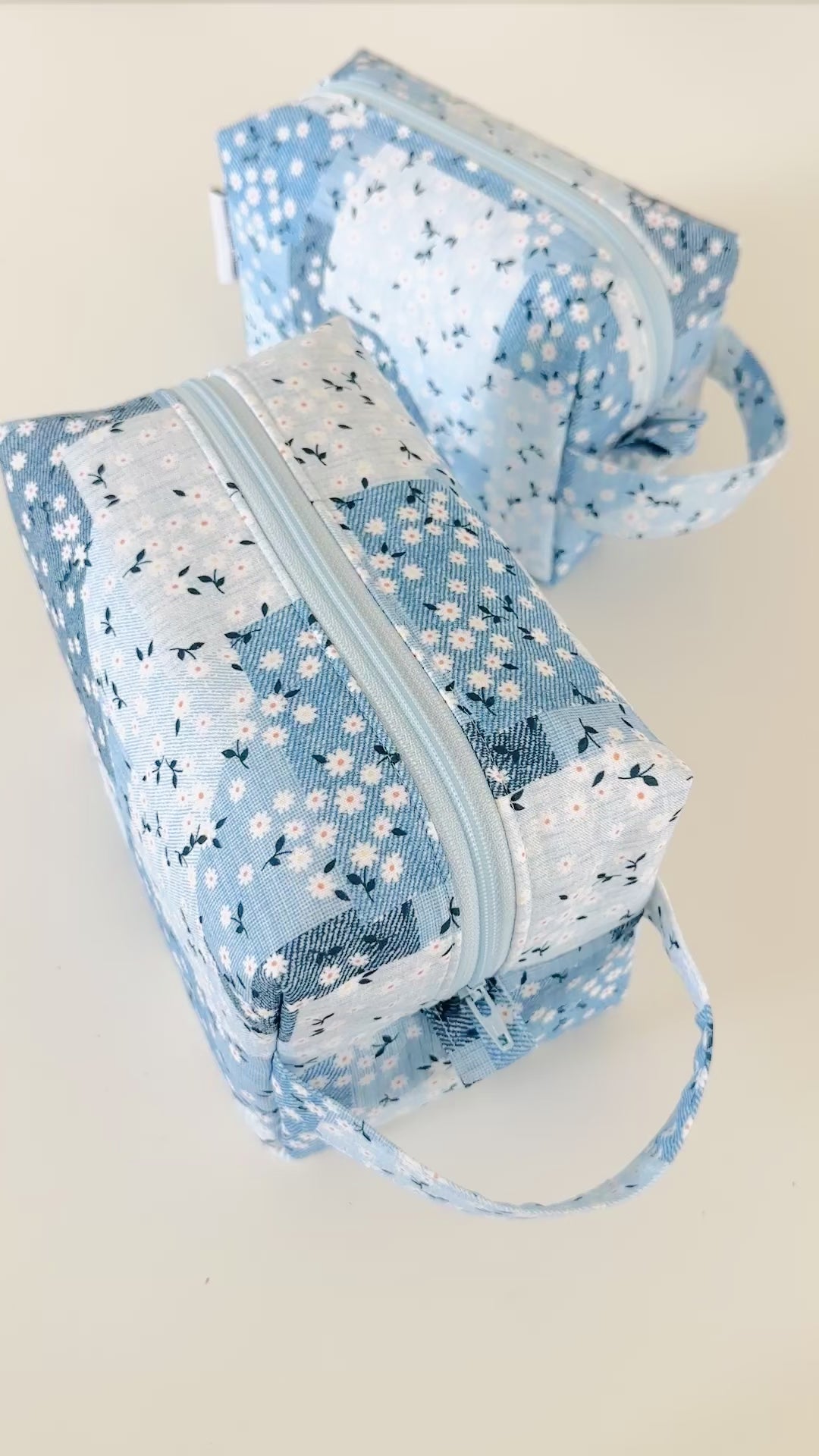 Three blue floral fabric pouches on a light background