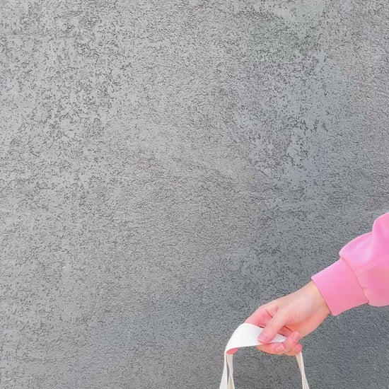 Tote bag with chicken and wildflower design held by a person in a pink jacket.